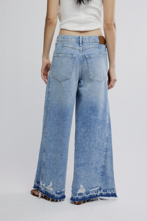 Wide-leg jeans with a white top on a plain background