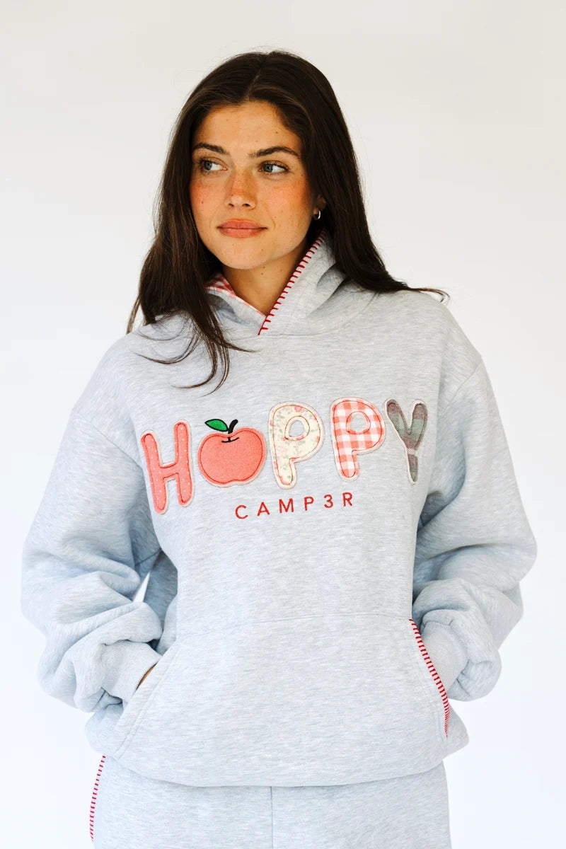 Woman wearing heather grey sweatshirt with red stitching around hood and &