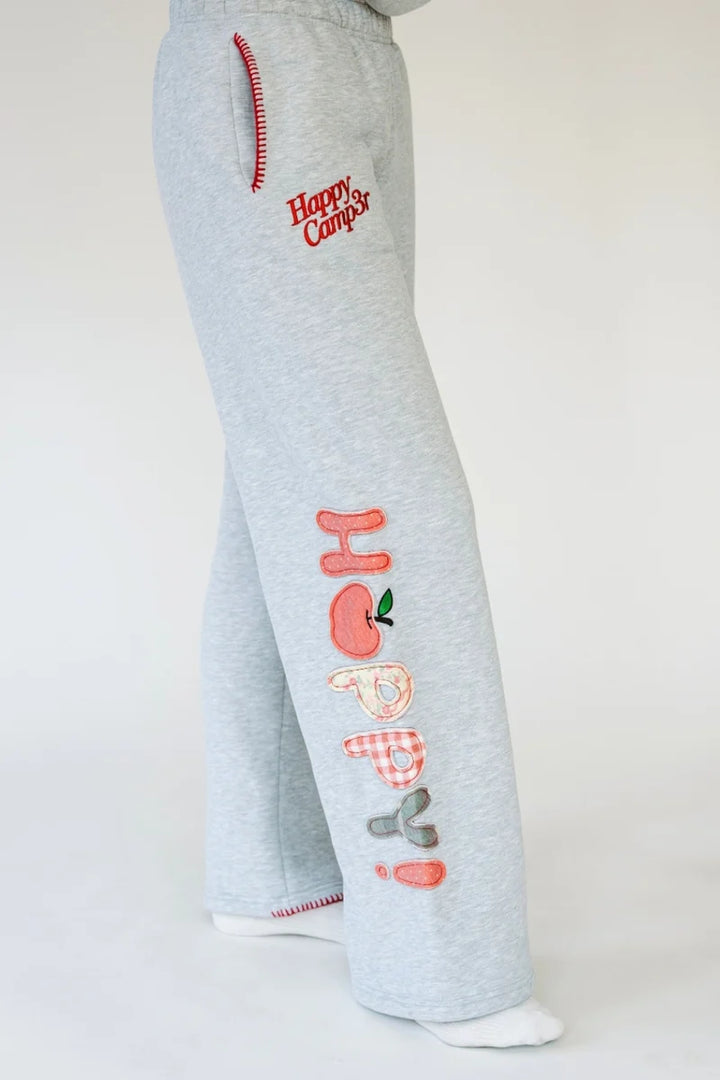 Person wearing heather grey sweatpants with red stitching on pockets and &
