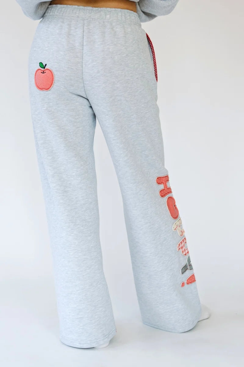 Person wearing heather grey sweatpants with apple applique on back and &