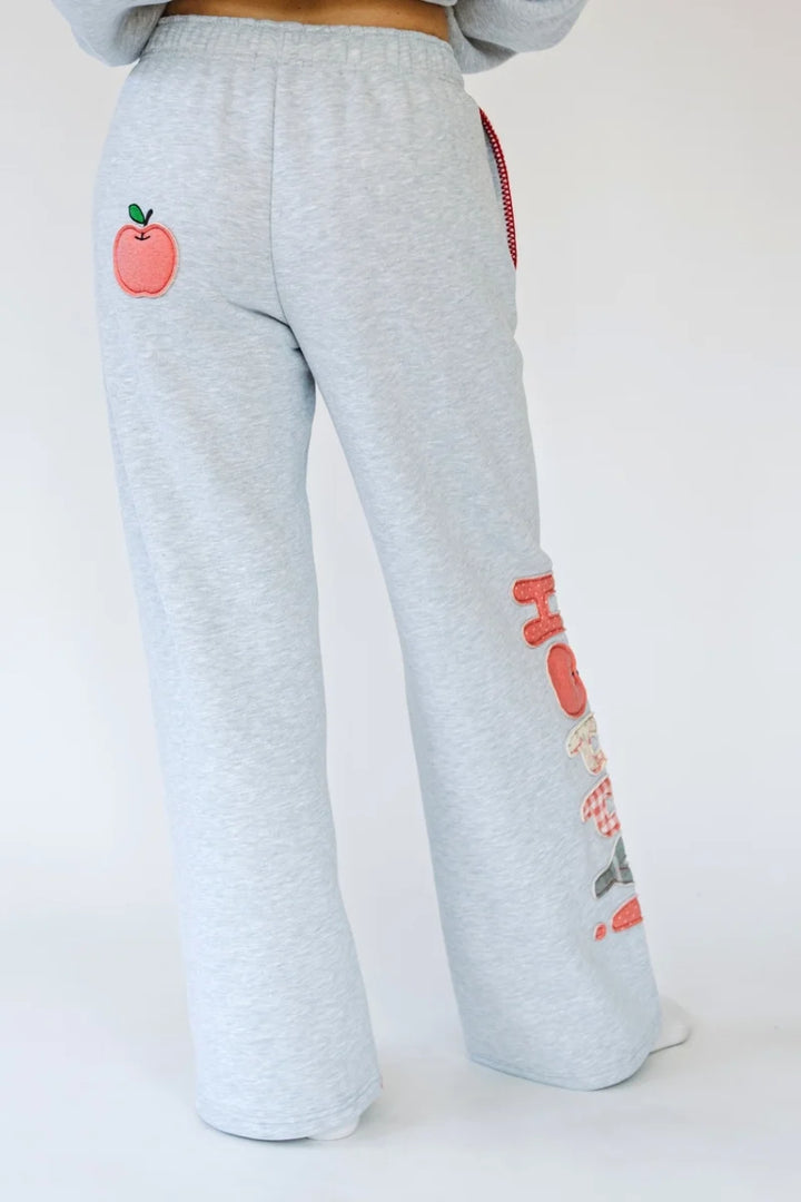 Person wearing heather grey sweatpants with apple applique on back and &