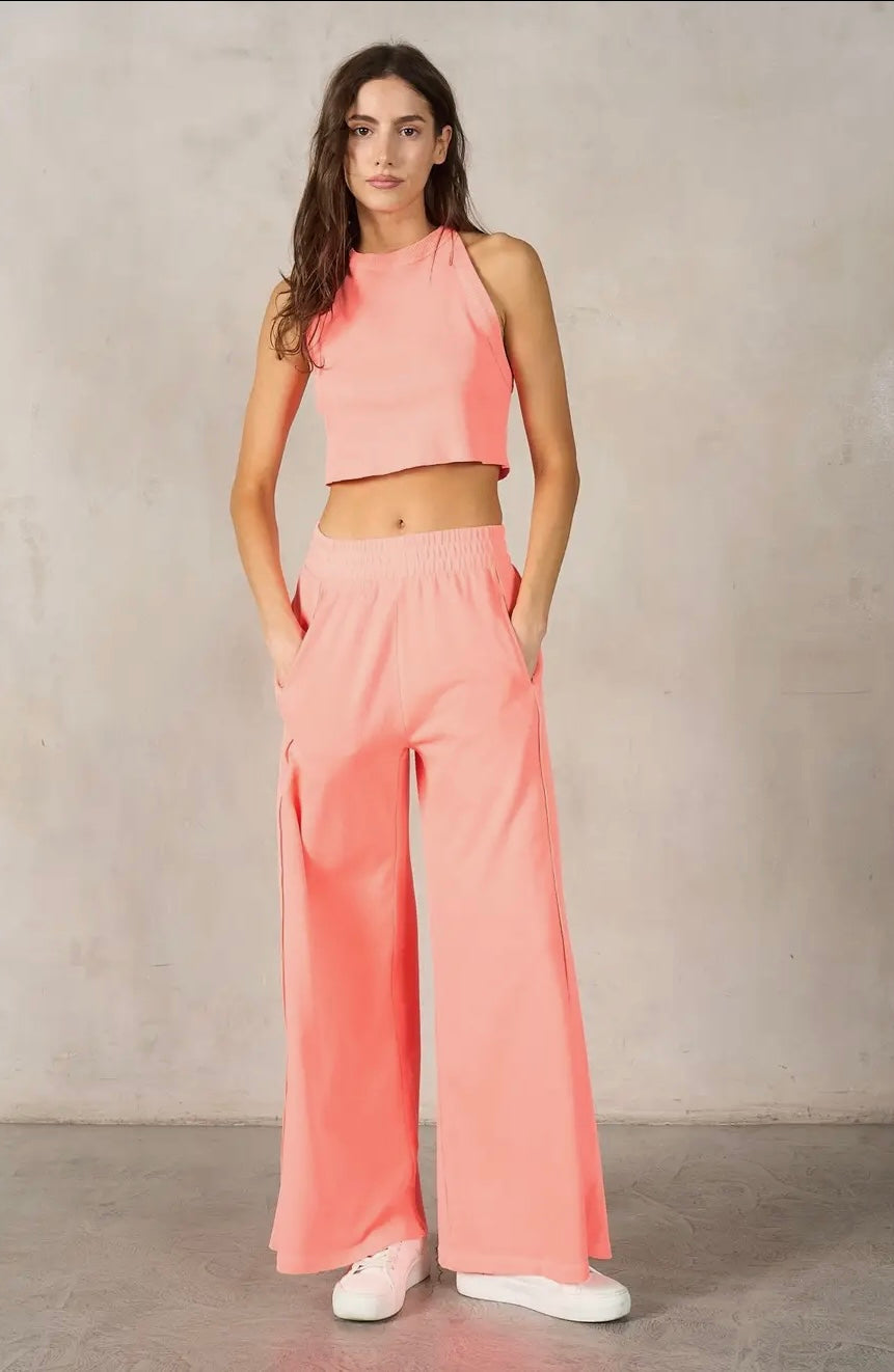 Woman wearing a pink outfit with wide-leg pants against a plain background