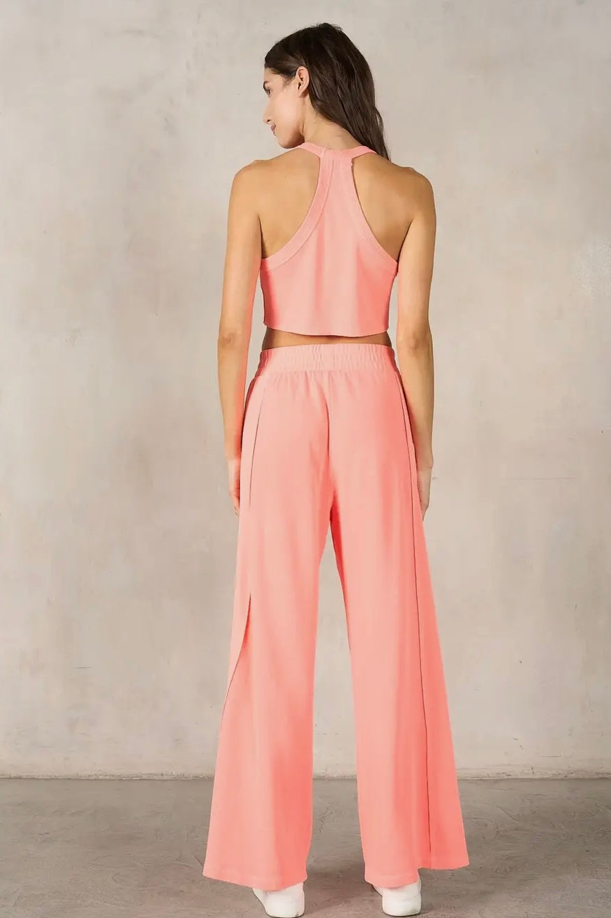 Woman wearing a pink outfit with wide-leg pants against a neutral background