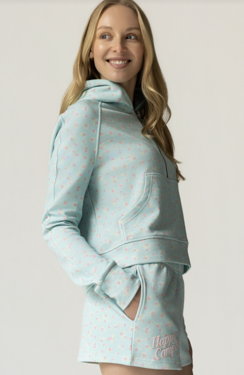 Woman wearing a light blue hoodie and skirt set with a pattern on a plain background