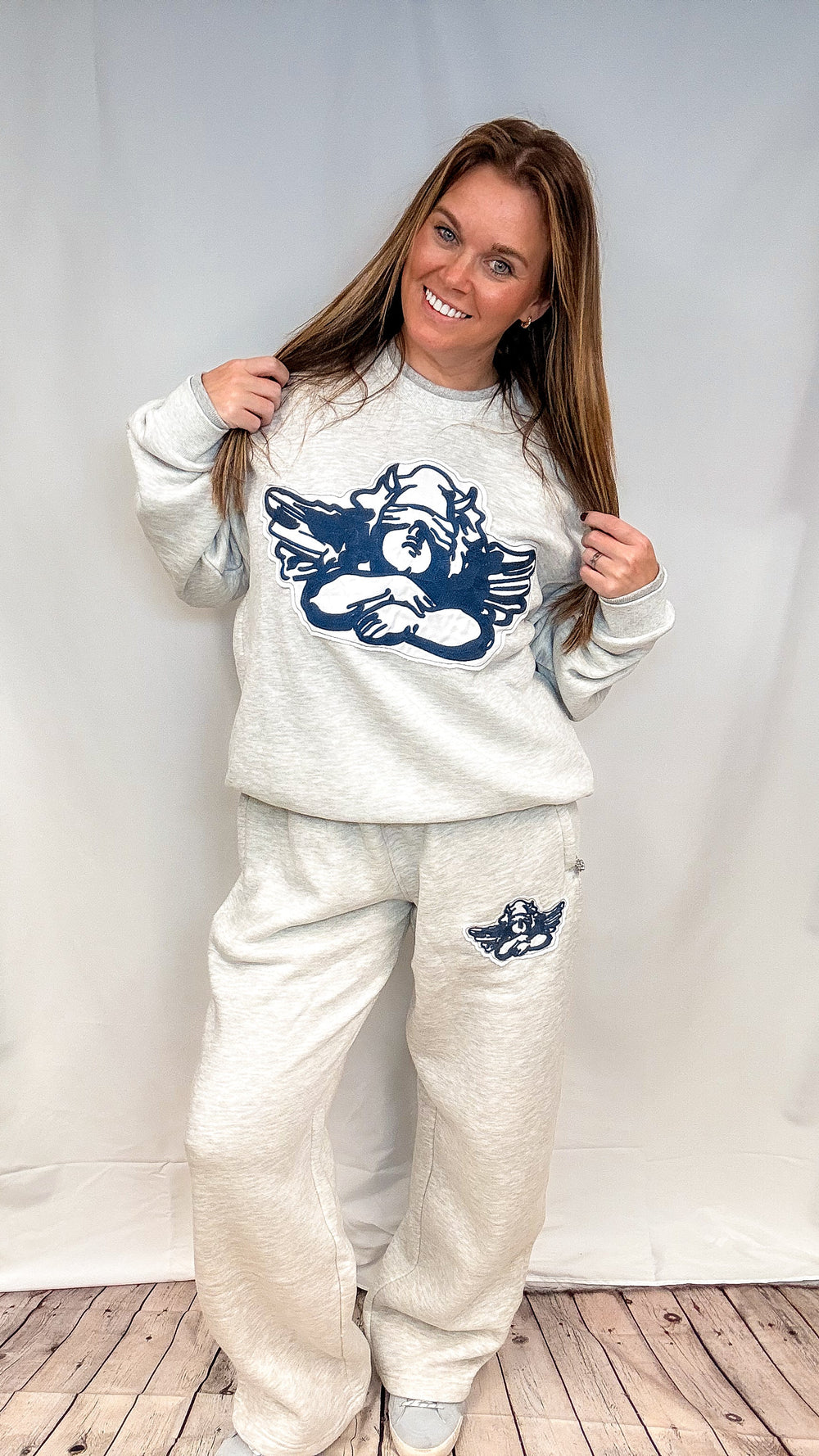 Woman wearing heather grey sweatsuit with cherub decal on white background