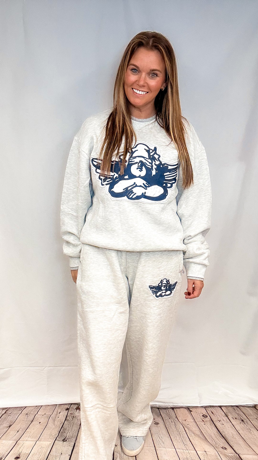Woman wearing grey sweatsuit with cherub decal on white background