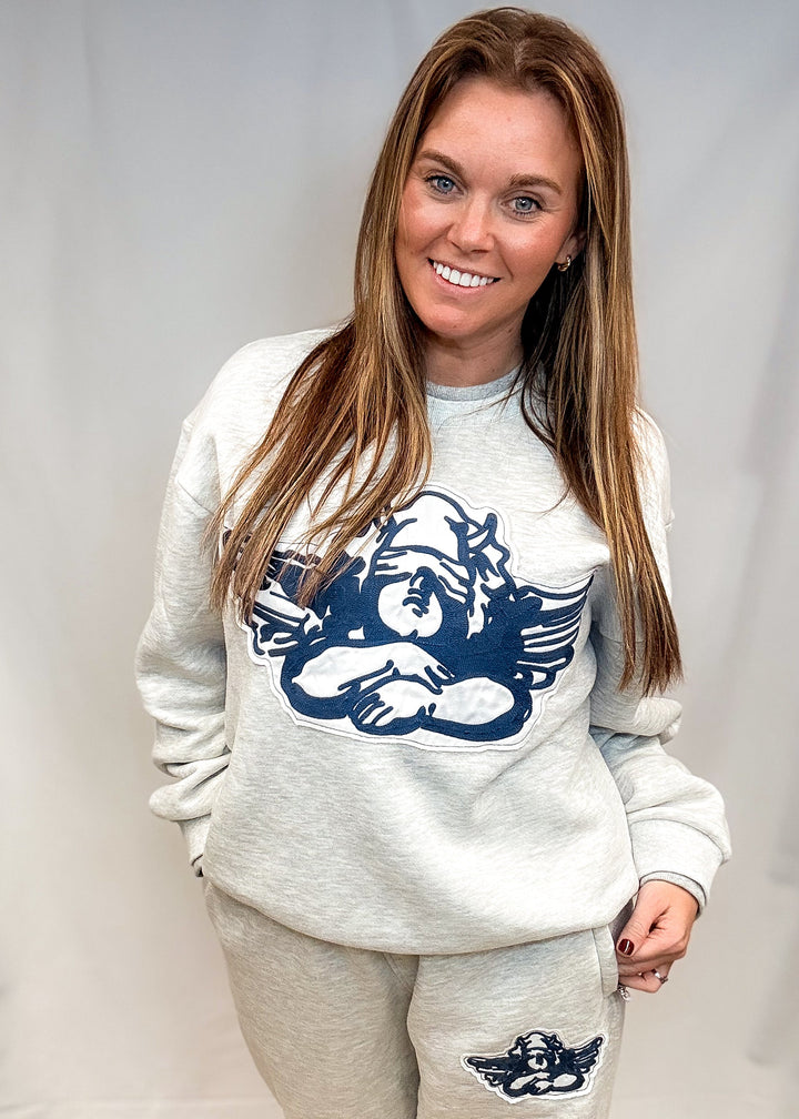 Woman wearing heather grey sweatsuit with cherub decal on front on white background