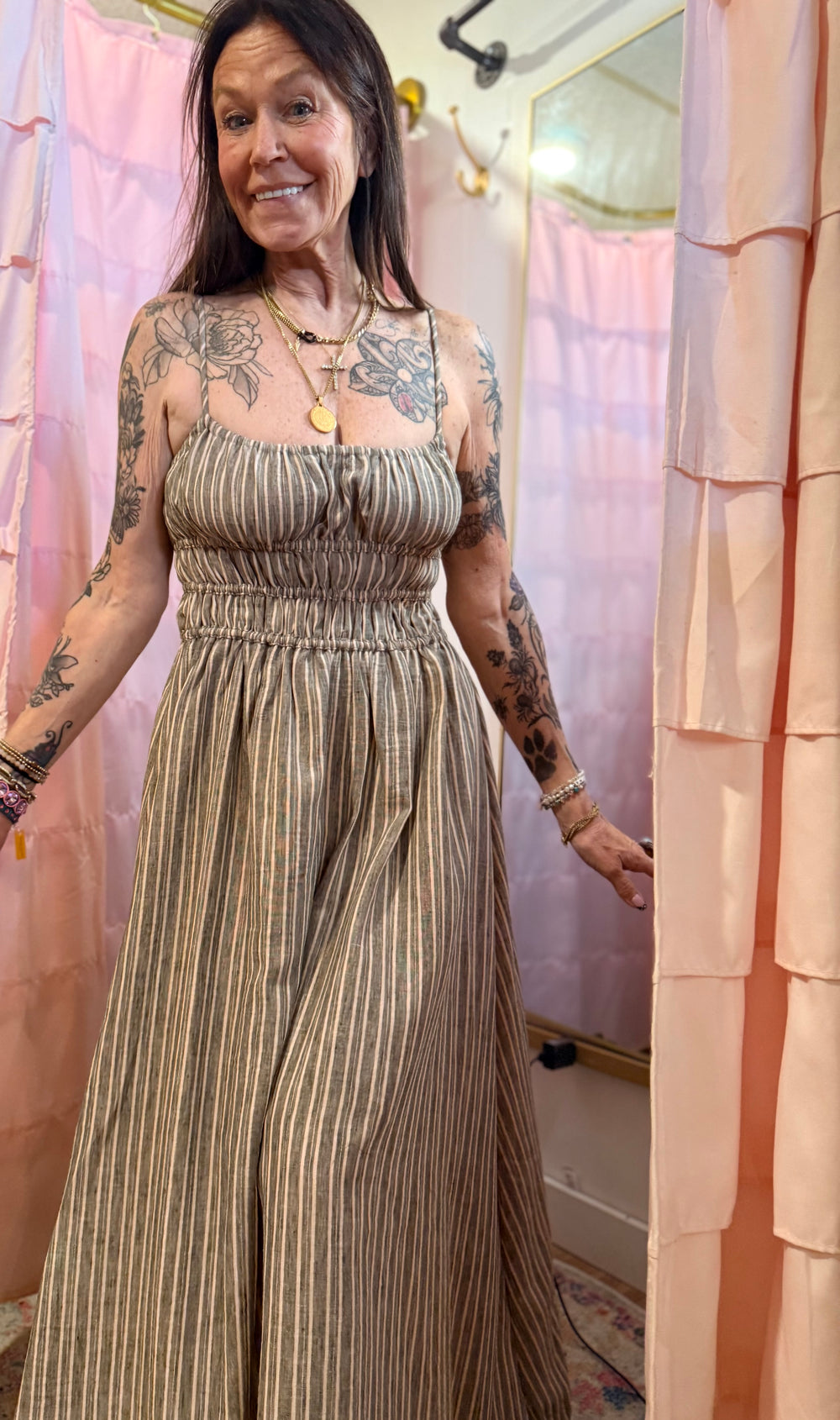 Woman wearing a long, patterned dress standing in front of a mirror.