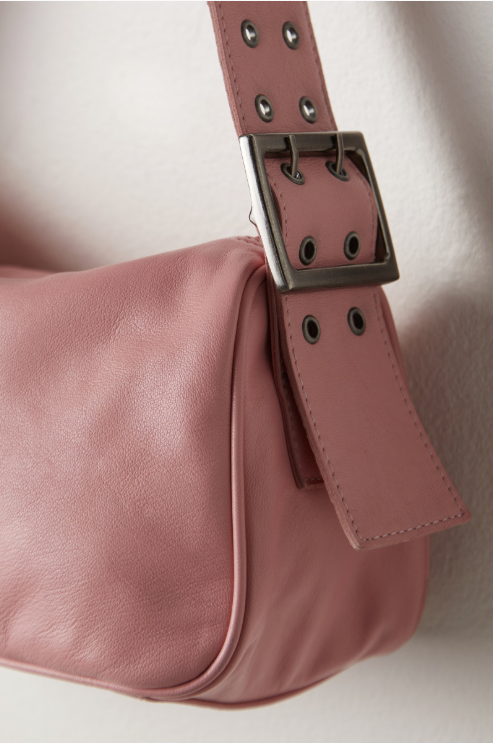 Close-up of a pink handbag with a silver buckle on a light background