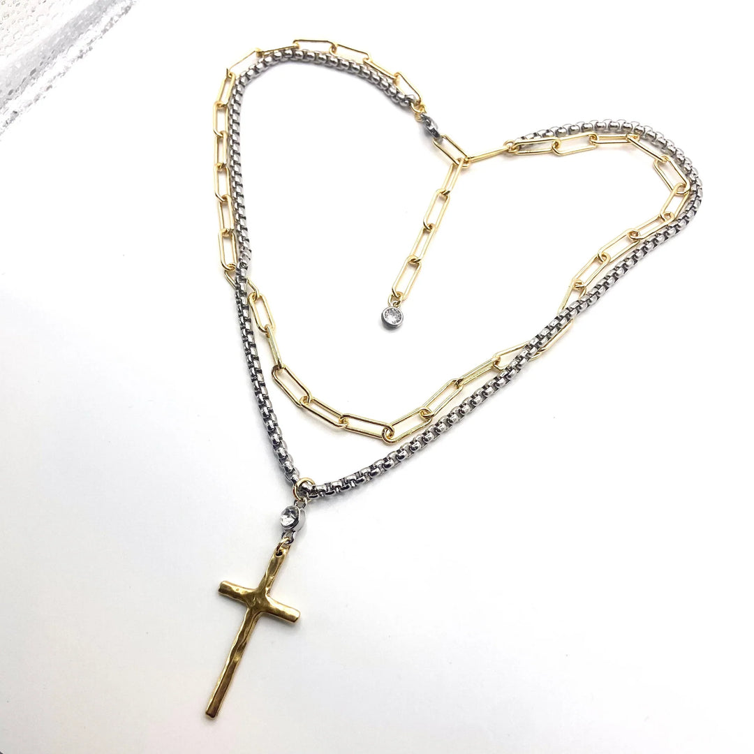 Necklace with gold and silver chain and cross pendant on a white background