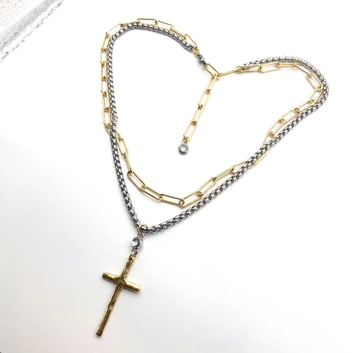 Necklace with gold and silver chain and cross pendant on a white background