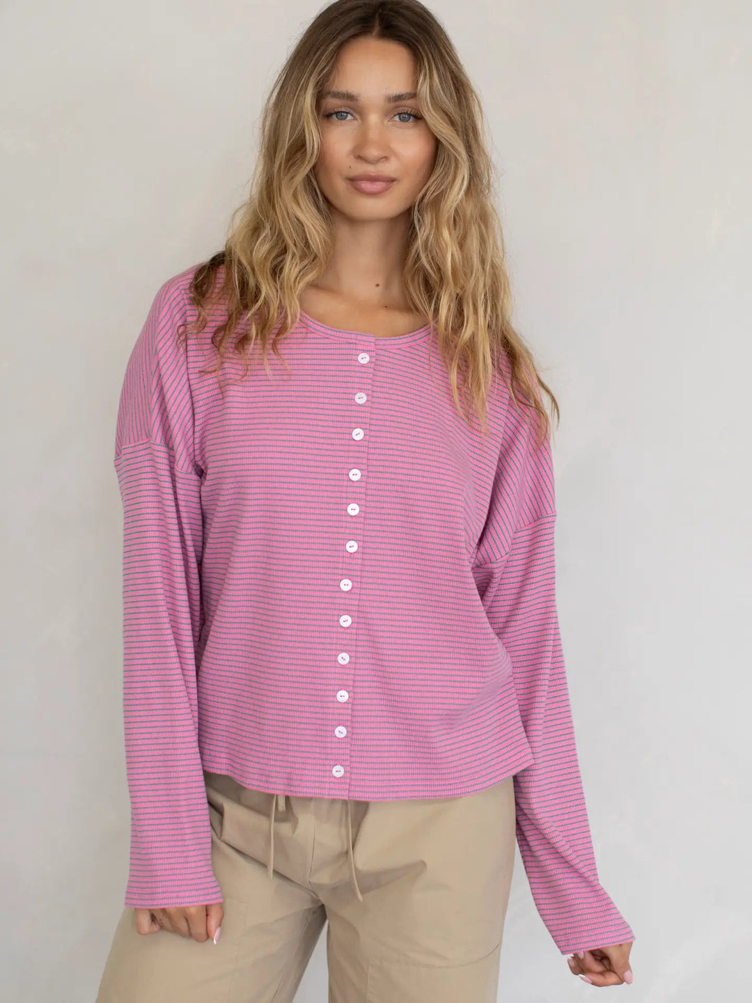 Woman wearing a pink striped shirt with a plain background