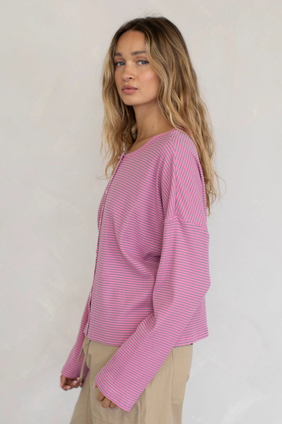 Woman wearing a pink striped sweater against a plain background