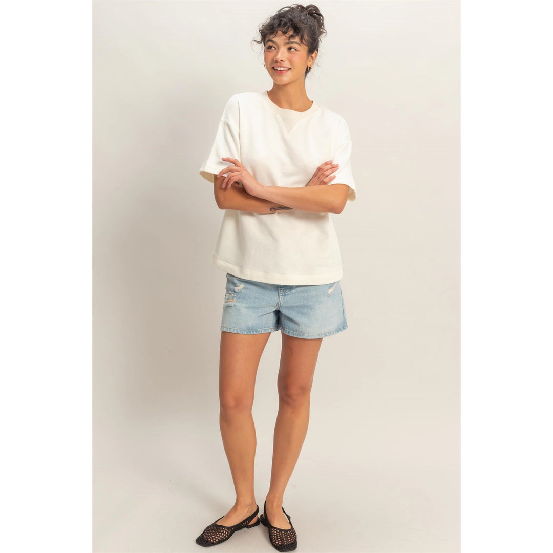 Person wearing a white t-shirt and denim shorts on a plain background