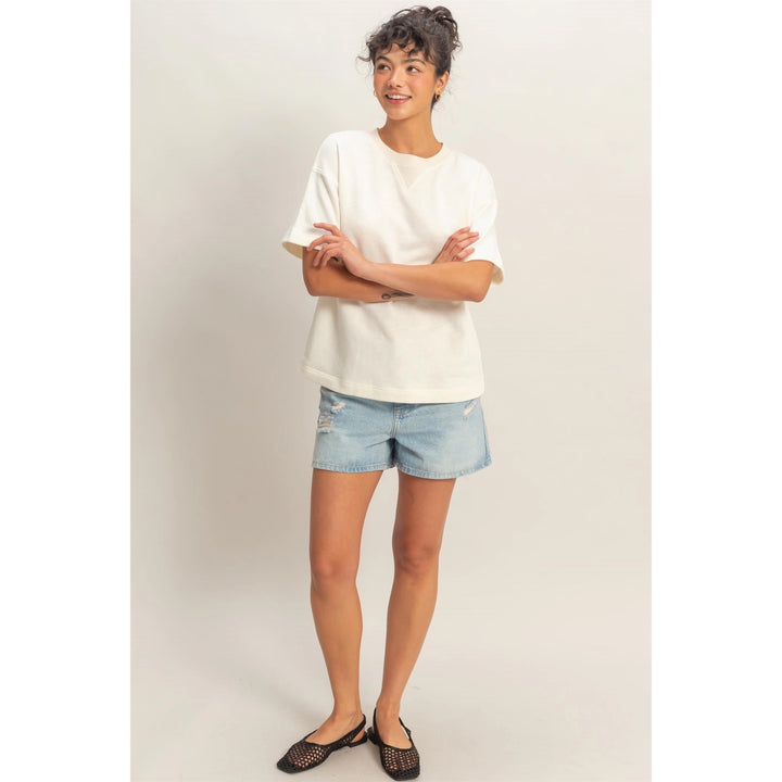Person wearing a white t-shirt and denim shorts on a plain background