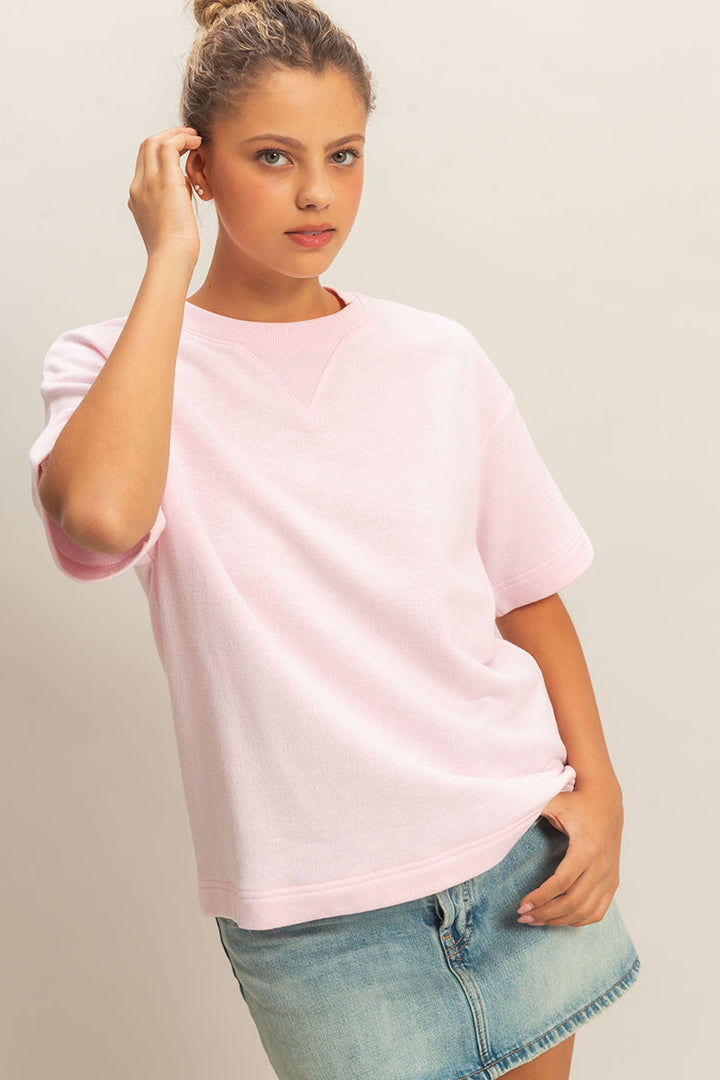 Woman wearing a light pink t-shirt and denim shorts on a plain background