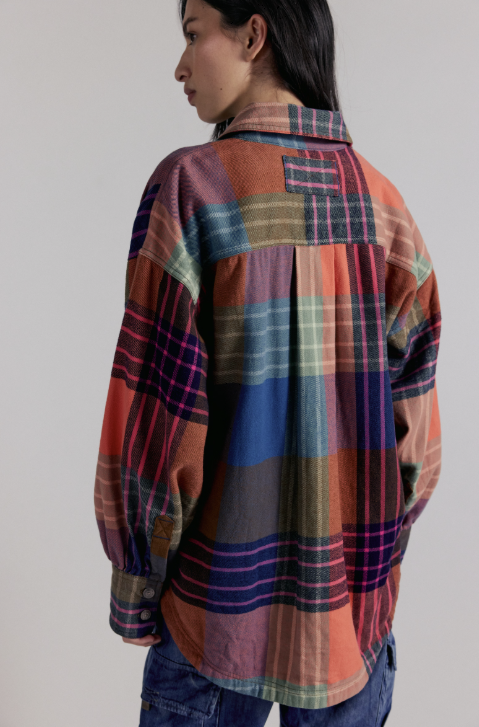 Person wearing a colorful plaid shirt against a plain background