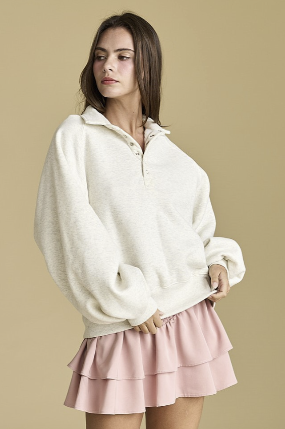 Woman wearing a heather grey sweatshirt with snap collar and pink skirt on plain background