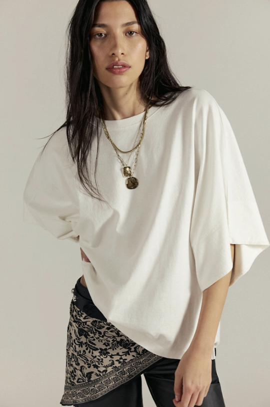 Woman wearing a white oversized shirt with a plain background