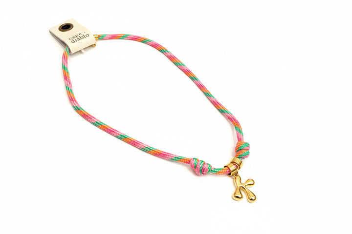 Cord necklace with gold bubble K on plain background