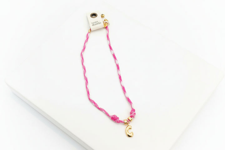 Pink and white braided lanyard with gold clip on plain background