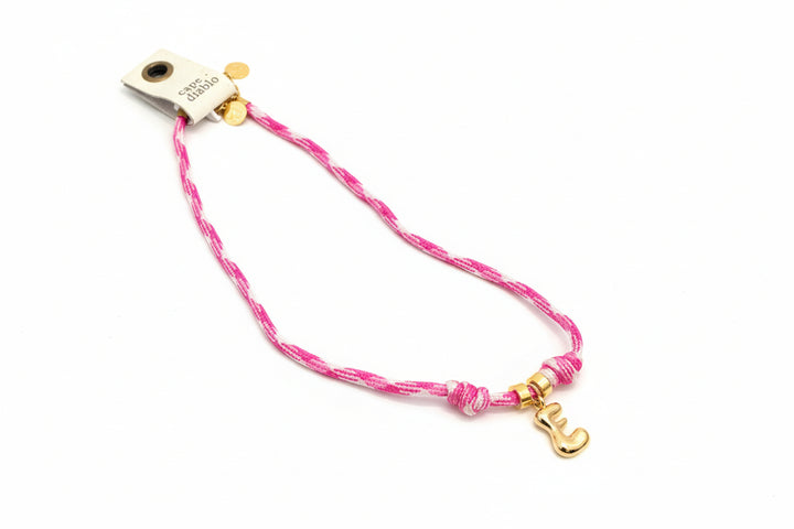 Cord necklace with gold bubble E on plain background