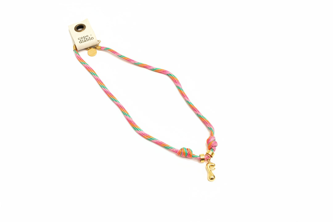 Cord necklace with gold bubble F on plain background