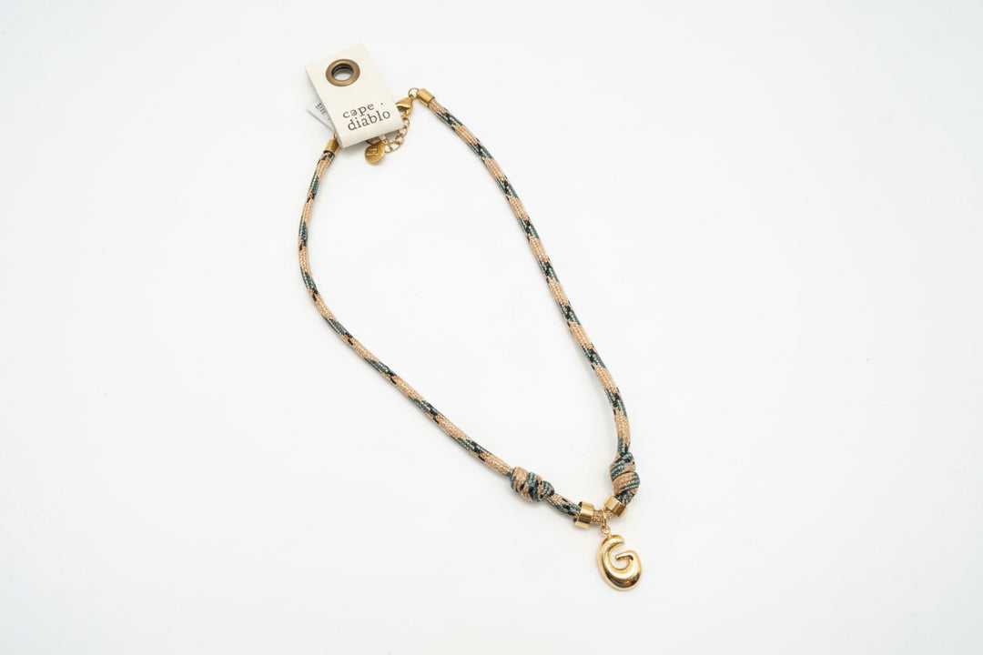 Cord necklace with gold bubble G on plain background