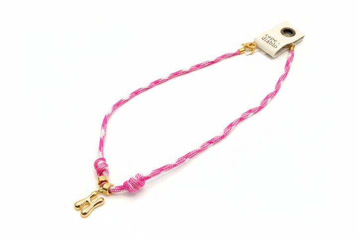 Cord necklace with gold bubble H on plain background