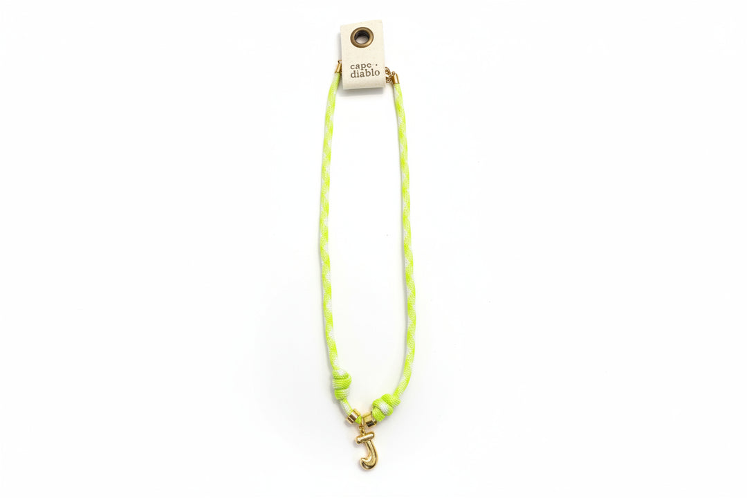 Cord necklace with gold bubble J on plain background