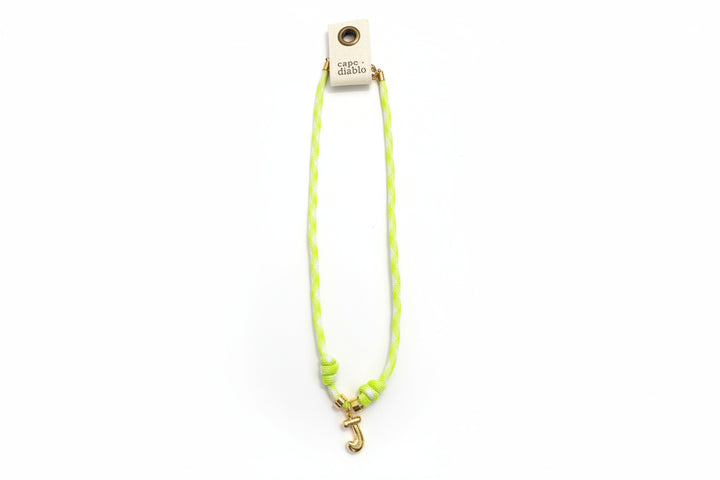 Cord necklace with gold bubble J on plain background