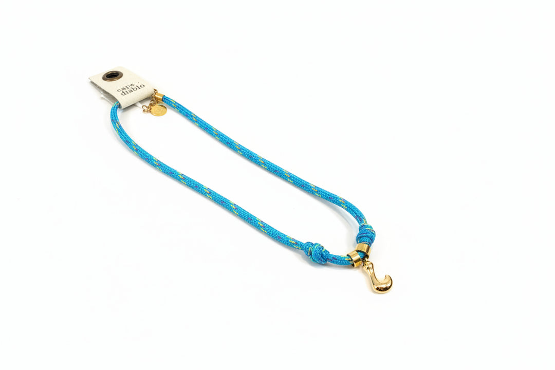 Cord necklace with gold bubble L on plain background