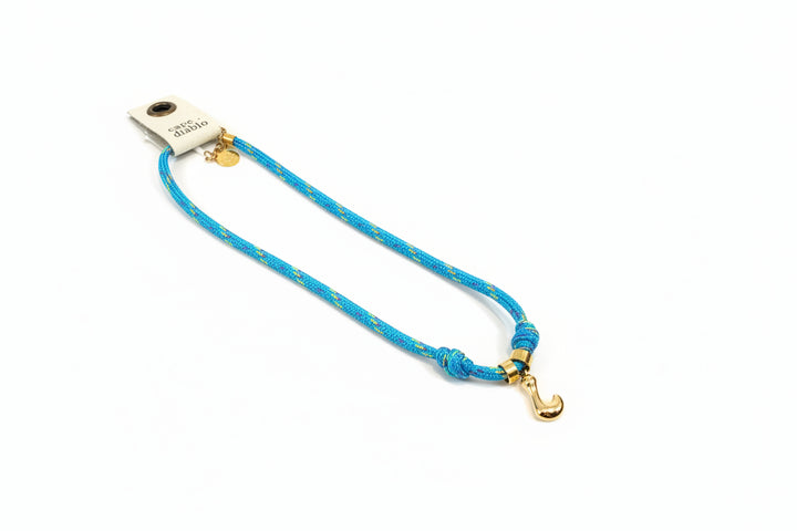 Cord necklace with gold bubble L on plain background
