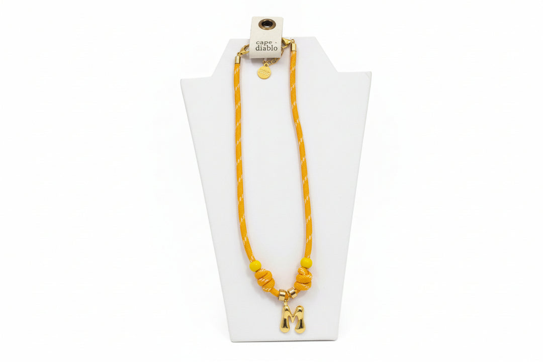 Cord necklace with gold bubble M on plain background
