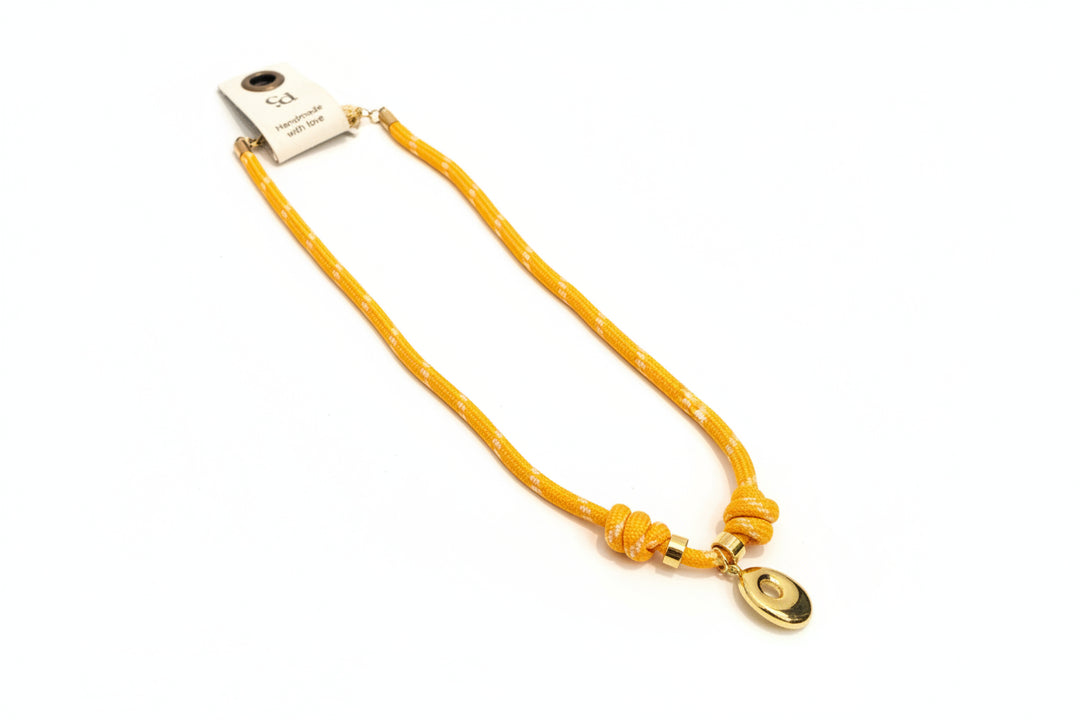 Cord necklace with gold bubble O on plain background