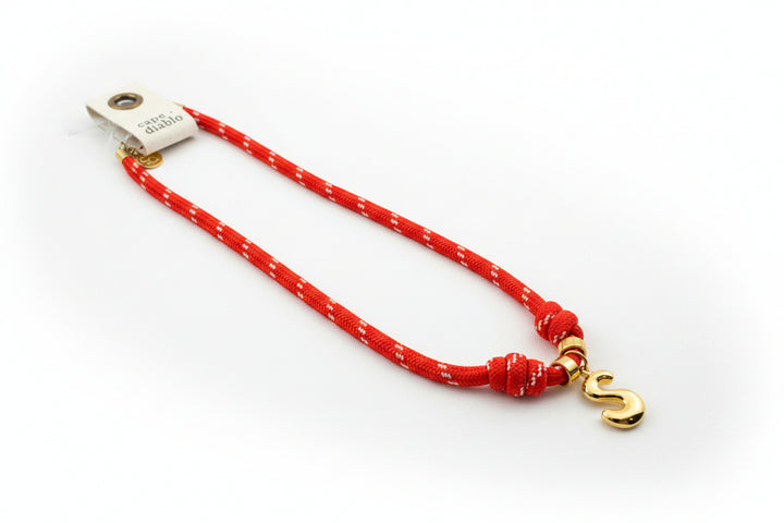 Cord necklace with gold bubble S on plain background