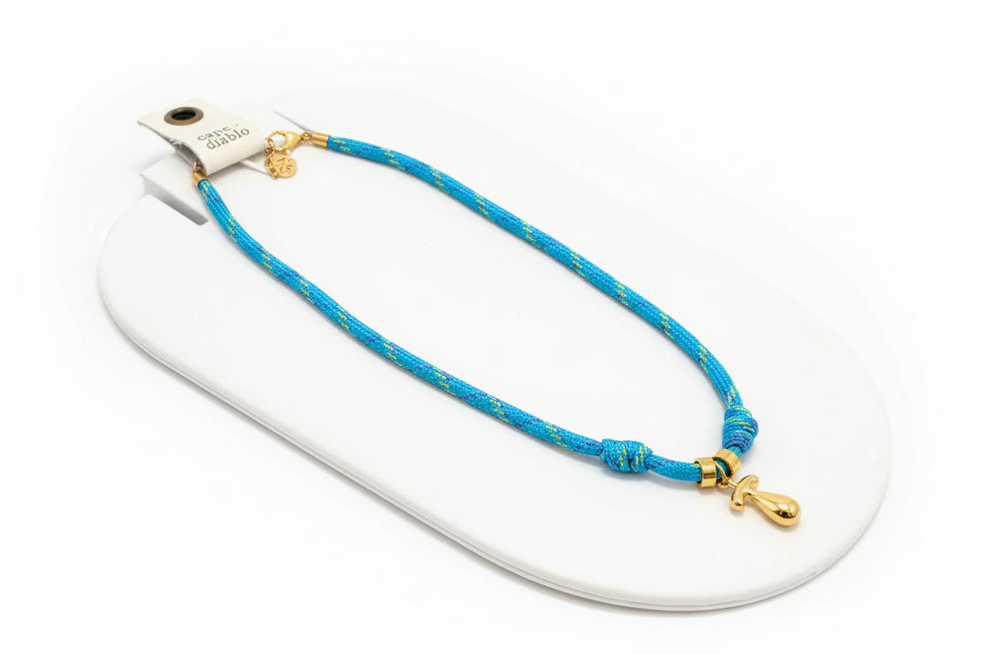 Cord necklace with gold bubble T on plain background