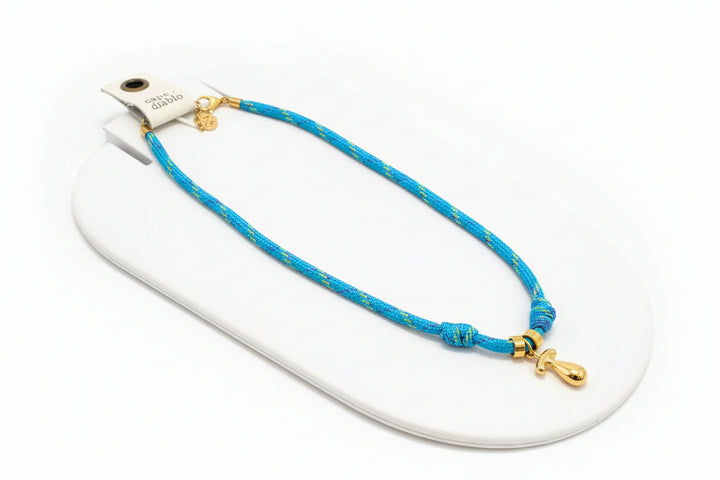 Cord necklace with gold bubble T on plain background