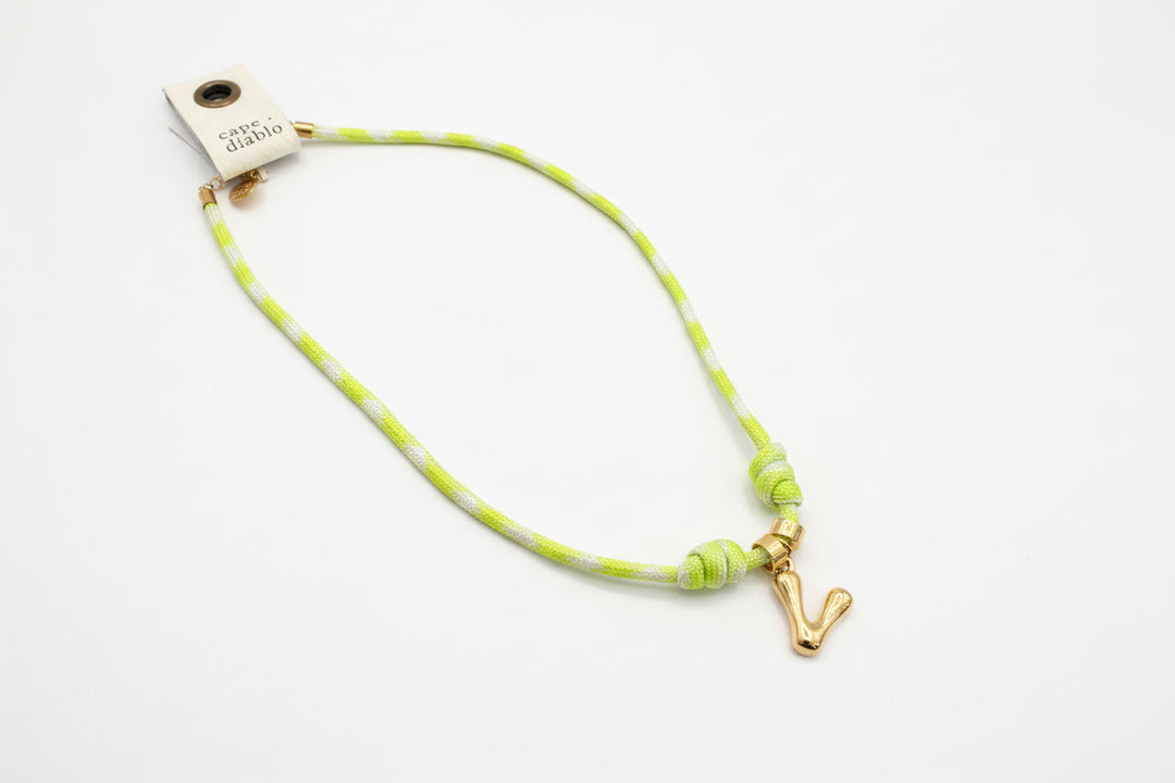 Cord necklace with gold bubble V on plain background