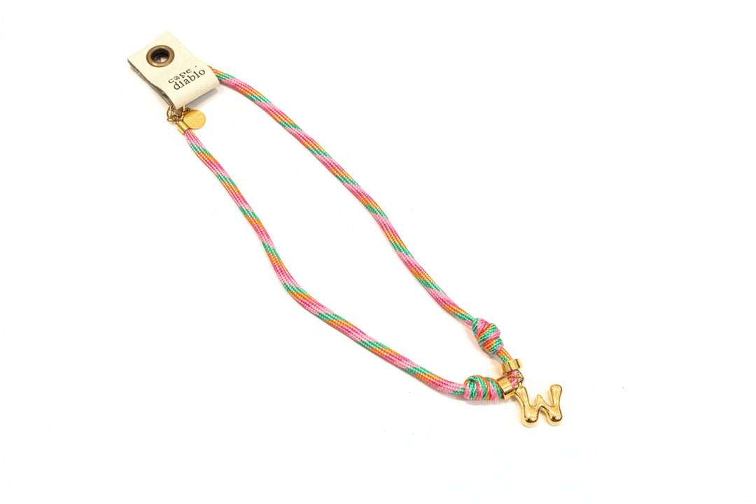 Cord necklace with gold bubble W on plain background