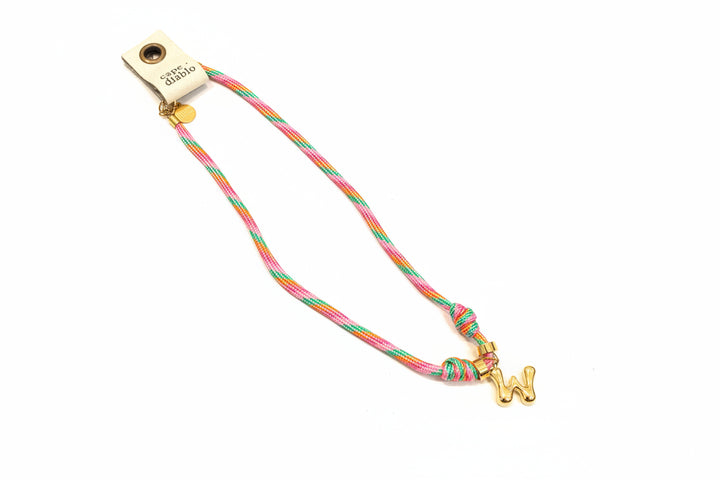 Cord necklace with gold bubble W on plain background