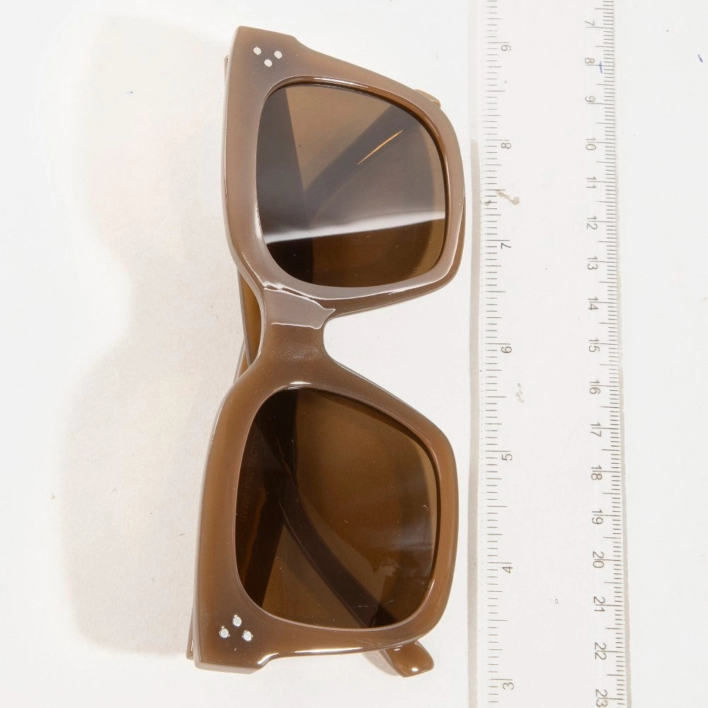 Brown sunglasses with a ruler for scale on a white background