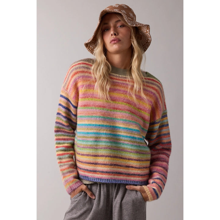 woman wearing rainbow sweater and bucket hat on plain background