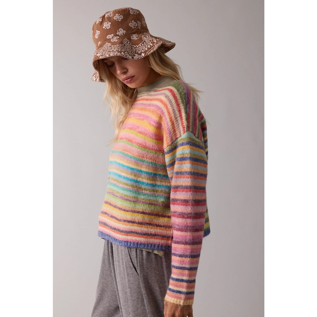 woman wearing rainbow sweater and bucket hat on plain background