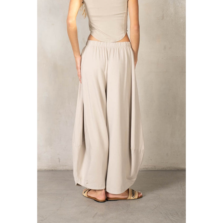 Back of woman wearing matching beige set on plain background