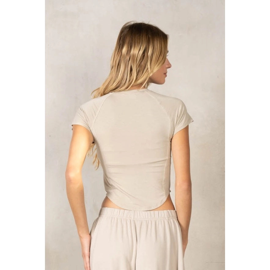 Back of woman wearing matching beige set on plain background