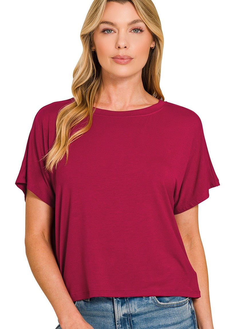 Woman wearing a maroon t-shirt with blue jeans on a white background