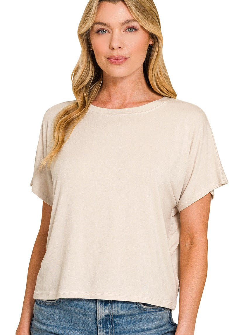 Woman wearing a sand beige t-shirt with blue jeans on a white background