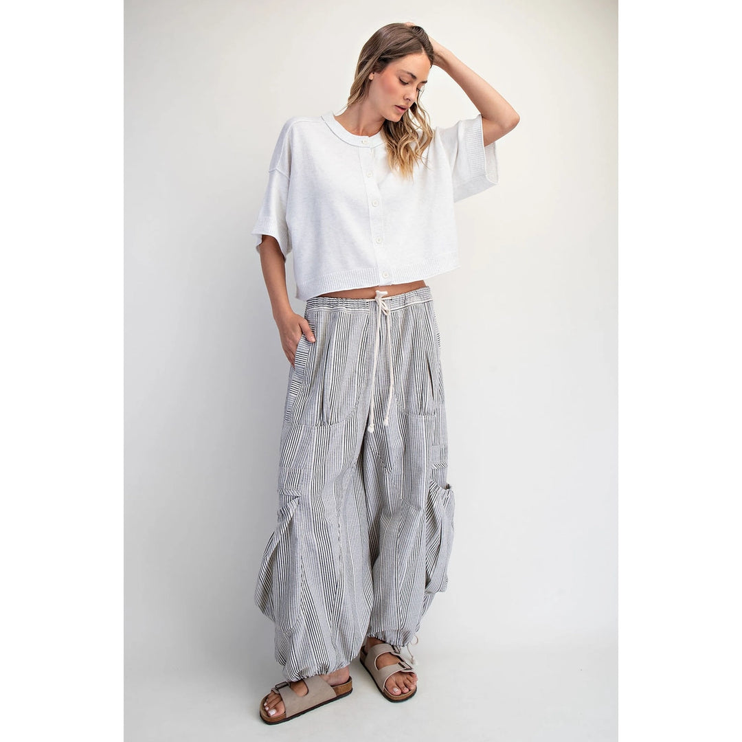 Woman wearing a white top and striped pants on a plain background