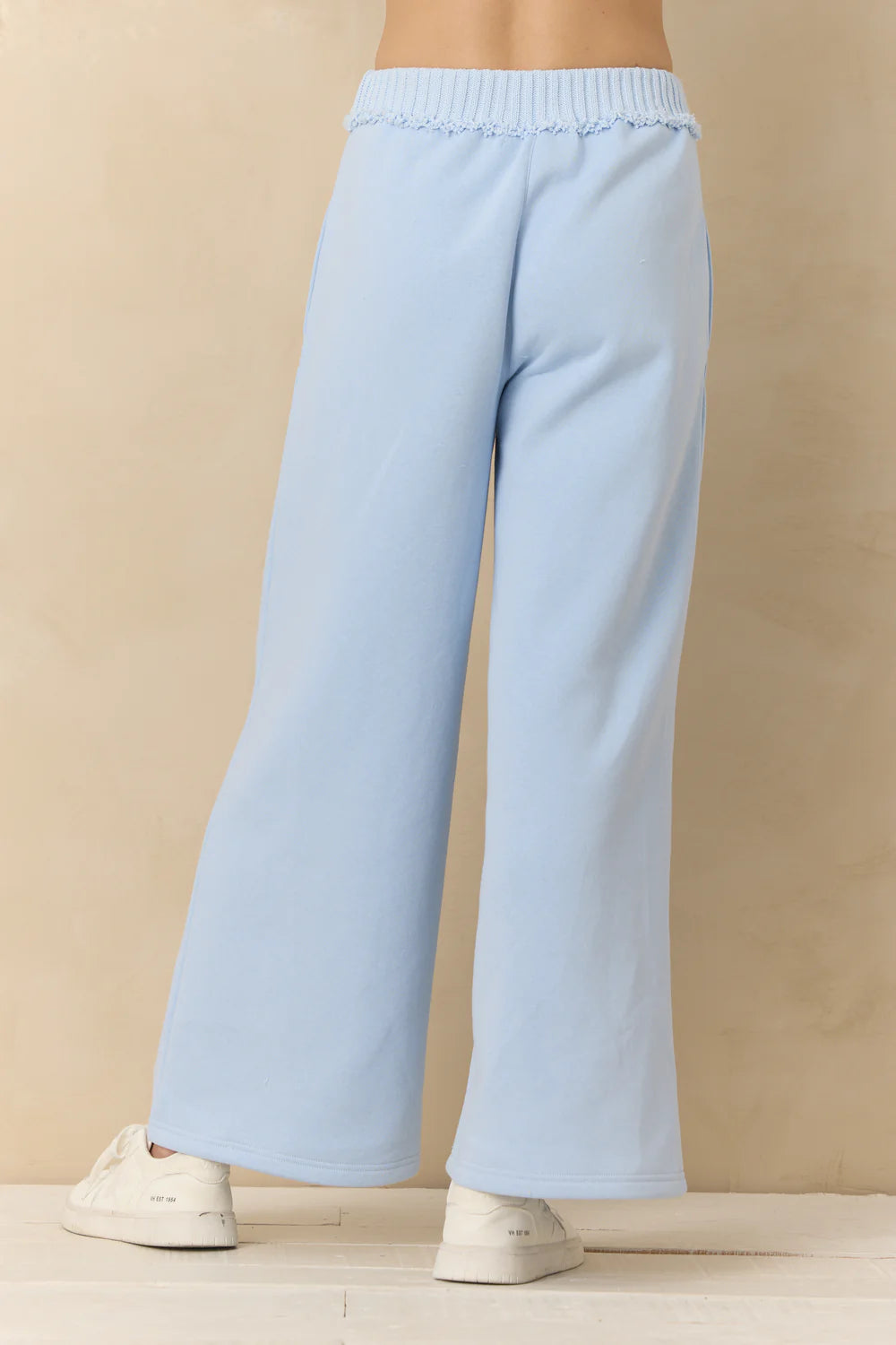 Light blue wide-leg pants worn by a person on a beige background